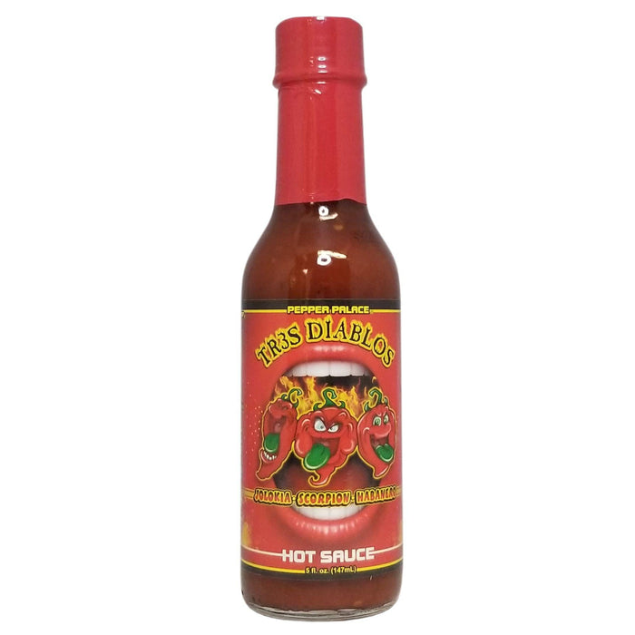 Bottle of Trs Diablos hot sauce with a red cap on a white background