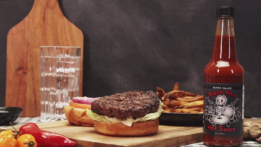 black rose hot sauce being poured on a hamburger