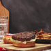 black rose hot sauce being poured on a hamburger