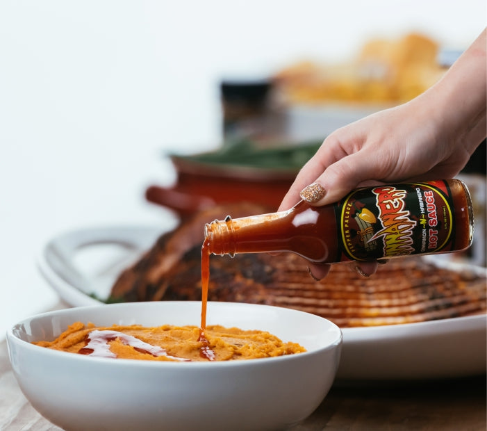 Cinnamon Habanero Hot Sauce being poured on Sweet Potatoes